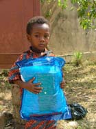 Child holding a mosquito net in Togo. There are still insufficient
								numbers of nets in many countries. 